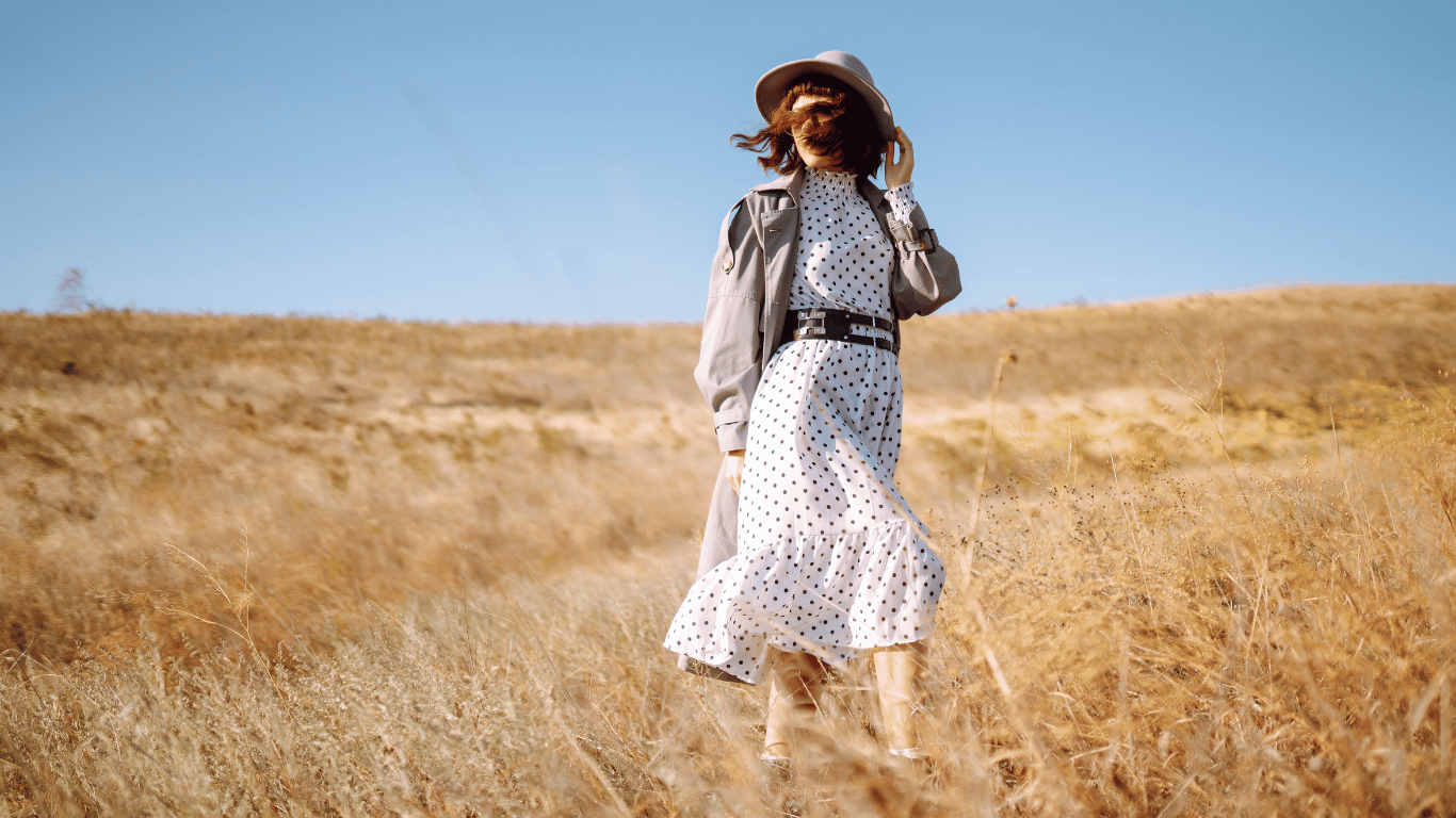 woman on wheat grass wearing a hat and coat