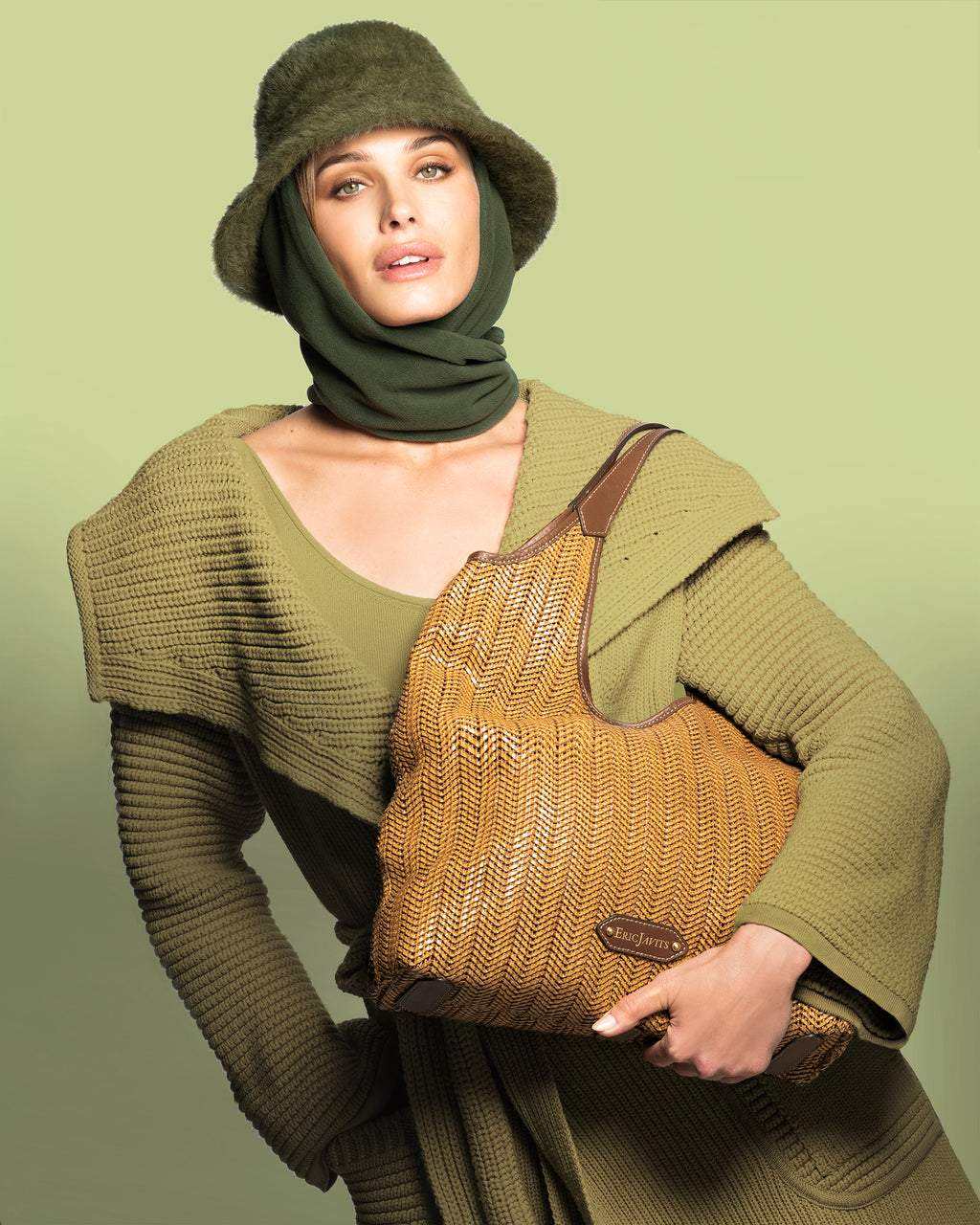 Woman wearing the Fuzzy Bucket hat with scarf in ivy, carrying a woven tan leather shoulder bag