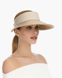 Woman wearing a beige sun visor, light background., eric jarvis hat, visor hat