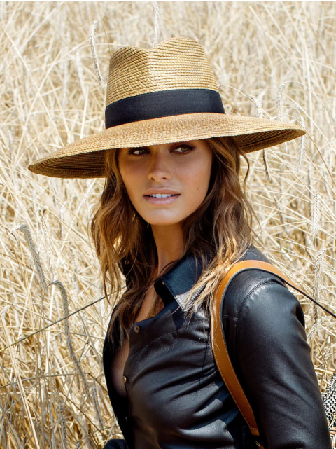 Woman in straw hat and black jacket in a dry field., eric jarvis hat, eric javits champ
